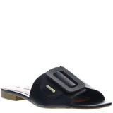 Zuecos de cuero negro con diseño de punta abierta y una hebilla decorativa grande en el empeine. Presenta una placa metálica pequeña con el logo de la marca y una suela plana de bajo perfil.