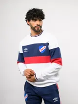 Buzo de cuello redondo confeccionado en felpa, con diseño de bloques de color en azul, rojo y blanco. Presenta el logo de Umbro y el escudo del Club Nacional de Football bordados en el frente.