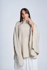 Poncho tejido color beige, con cuello alto y corte asimétrico.