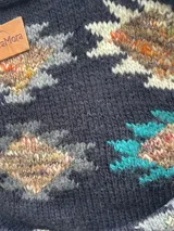 Saco tejido a mano de color negro, con diseño geométrico multicolor, cuello smoking y cierre frontal con dos botones.