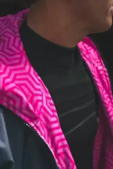 Campera con capucha de diseño impermeable, color gris en la parte superior y negro en la inferior, con cierre frontal y forro interior fucsia con estampa animal print. Presenta estampado gráfico de la marca Blue Moon en el pecho.