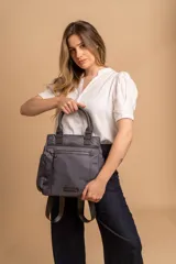 Cartera mochila de diseño versátil, color rosado, confeccionada en material sintético impermeable. Cuenta con doble asa superior, correas ajustables para usar como mochila, compartimento principal con cierre y bolsillo frontal con cierre decorado con tirador largo.