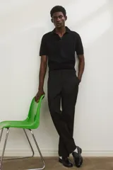 Pantalón de vestir negro, corte recto y holgado, con pliegues marcados en el frente y pretina clásica con cierre y botón.