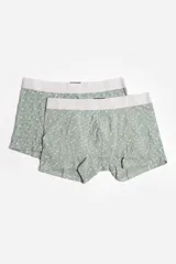 Pack de dos boxers para hombre en color verde, con cintura elástica en tono gris claro. Uno de los boxers presenta un estampado de puntos pequeños y el otro un estampado de líneas en zigzag.