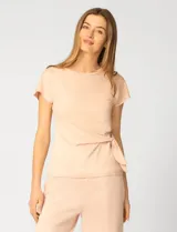 Remera de manga corta color beige, confeccionada en mezcla de modal, con cuello redondo y detalle de lazo lateral que genera un drapeado natural en la cintura.