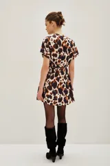 Vestido corto de escote cruzado en V, con mangas cortas tipo kimono y cintura elástica. Presenta un estampado animal print abstracto en tonos marrones, azul oscuro y crema.
