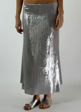 Conjunto plateado brillante de top con breteles finos y pollera larga con efecto mojado.