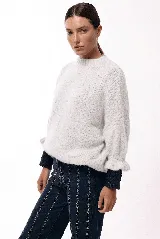 Sweater de tejido de punto con silueta relajada, cuello redondo y mangas 3/4 abullonadas con puños ajustados que aportan volumen.