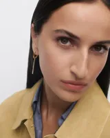 Aros colgantes dorados con forma de argolla y barra vertical de circonitas blancas.