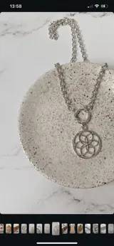 Collar de cadena de eslabones gruesos con dije circular de diseño geométrico tipo mandala, con cierre frontal de argolla.