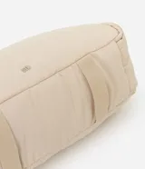 Cartera tipo shopper de gran tamaño, confeccionada en poliéster con acabado acolchado y textura lisa. Presenta un diseño de trapecio invertido con correas integradas para llevar al hombro y cierre superior con cremallera.