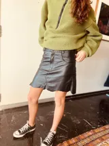 Pollera corta de cuero ovino color suela, con diseño de paneles y costuras visibles, cierre frontal y bolsillos laterales.