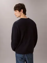 Sweater de punto color azul marino, de manga larga, con cuello redondo y logo institucional en relieve al tono en el pecho.