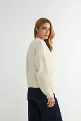 Cardigan de tejido de punto jaspeado en tonos rosados y violetas, con cuello redondo y cierre frontal de botones marrones.
