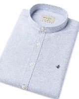 Camisa de lino y algodón color celeste, con cuello mao, cierre frontal de botones claros y pequeño bordado de pato en el pecho.