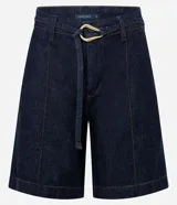 Bermuda de jeans azul oscuro, tiro medio, con costuras contrastantes y cinturón de lazo de tela con hebilla metálica de forma irregular.