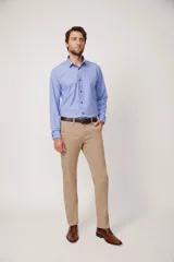 Pantalón de vestir color beige, de corte recto, con bolsillos laterales y traseros. Se ajusta a la cintura con cinturón de cuero marrón.