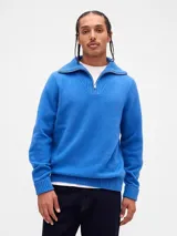Buzo de tejido de punto suave color azul, con cuello alto y cierre frontal parcial. Presenta puños y ruedo acanalados.
