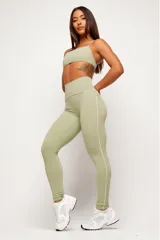 Calza deportiva de tiro alto color verde claro, con costuras laterales en contraste de color blanco que recorren la prenda desde la cintura hasta los tobillos.