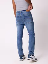 Jean de corte slim fit en color azul lavado, con diseño clásico de cinco bolsillos, cierre frontal con botón y costuras en contraste.