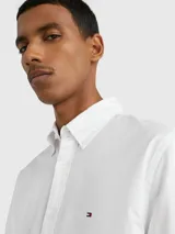 Camisa blanca de manga corta confeccionada en popelín de puro algodón, con cuello abotonado, corte regular y logo de Tommy Hilfiger bordado en el pecho.