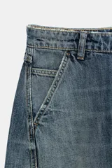Jeans de tiro medio y corte barrel con diseño de perneras curvadas, tiro medio, trabillas para cinturón y cinco bolsillos. Presenta lavado clásico y costuras pespunteadas decorativas en la parte delantera.