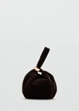 Bolso de mano pequeño confeccionado en terciopelo color marrón oscuro, con diseño fruncido y detalle de aro metálico dorado en el asa.