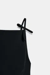 Top rosado de escote recto con tirantes finos que se anudan en la parte superior. Presenta costuras que realzan la figura y cierre con cremallera oculta en la costura lateral.