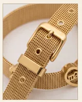 Pulsera de acero con baño de oro, compuesta por una malla metálica flexible y tres dijes pasantes: un corazón con la palabra 'Mamá' grabada, una figura de niña y una figura de niño.