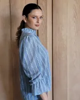 Blusa de algodón con cuello mao y volados, mangas largas con puños elásticos y corte holgado.