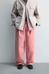 Pantalón relaxed fit color rosado, confeccionado en tejido de algodón con efecto lavado. Presenta pliegues frontales, bolsillos delanteros y bolsillos traseros de vivo. Cierre frontal con cremallera y botón.