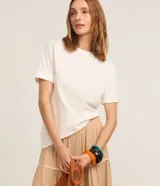 Remera básica de manga corta con vuelta en los puños, cuello redondo y corte recto, de color blanco.