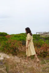 Vestido túnica a rayas verticales color mostaza y blanco, con cuello redondo, mangas cortas abullonadas y lazo para atar en la cintura.