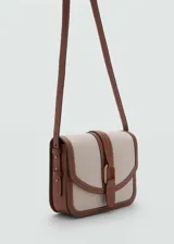 Bolso bandolera de diseño estructurado con cuerpo de tejido efecto rafia en color beige y detalles de ribetes y correa en cuero sintético color marrón. Presenta una solapa frontal con cierre de hebilla decorativa y botón magnético, y una correa larga ajustable para llevar al hombro o cruzado.
