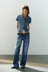 Camisa entallada de denim de manga corta, cuello camisero, bolsillos delanteros con solapa y cierre frontal de botones.