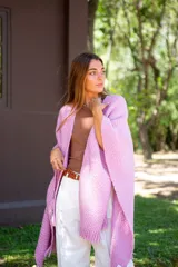 Ruana tejida color rosa con flecos en el borde inferior.