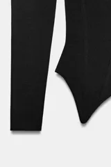 Top corsetero de punto color negro, con escote recto, hombros descubiertos, manga larga y bajo asimétrico.