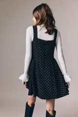 Vestido corto negro con estampado de lunares blancos, escote cuadrado, breteles anchos, cuerpo entallado y falda evasé con vuelo.