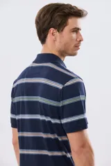 Remera polo de manga corta con diseño a rayas horizontales en tonos azules, celestes, verdes y beiges sobre base azul marino. Presenta cuello camisero con cierre frontal de botones y un pequeño logo bordado en el pecho.