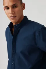 Camisa de manga larga azul marino, con cuello abotonado y logo bordado en el pecho.