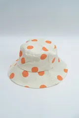 Gorro tipo bucket de color crema con estampado de lunares naranjas.