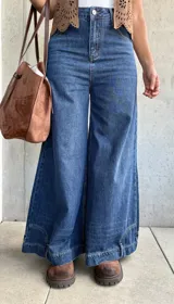 Jean de corte ancho y tiro medio, confeccionado en denim azul oscuro sin lycra. Presenta un diseño de pierna recta y holgada con costuras reforzadas.