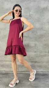 Vestido corto color bordó, con breteles finos que se atan en los hombros, corte recto y falda con volados.