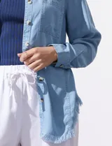 Camisa celeste de tencel, marca Hester & Orchand. Tiene cuello con solapa, escote en V, abertura central con botones, bolsillo aplicado en el frente y ruedo desflecado.