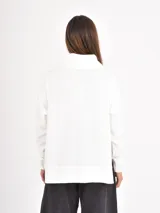 Polera de manga larga en color negro, confeccionada en tejido de punto con textura acanalada fina. Presenta un cuello alto tipo polera, corte holgado y puños ajustados.