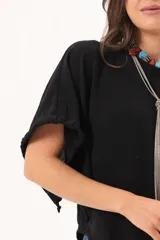 Blusa de silueta relajada y caída fluida, color negro, con escote redondo y mangas amplias.