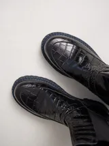 Bota tipo Chelsea de cuero con textura de reptil, color suela, con paneles elásticos laterales negros y suela de goma dentada con pespuntes en contraste.