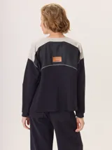 Buzo de manga larga con diseño color block. Cuerpo principal color camel, sección central de la espalda color azul marino liso y hombros con tejido de lana texturado en tonos azules. Posee un parche de cuero marrón con el logo grabado en la espalda.