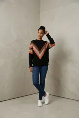 Sweater de tejido tricot con diseño chevron en forma de V en el frente, combinando colores marrón, blanco y fucsia. Presenta cuello redondo, mangas largas y terminaciones en rib.