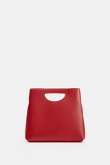 Bolso de mano de piel color rojo, con diseño de cuerpo asimétrico y asa de mano integrada con apertura lateral. Incluye correa bandolera extraíble y bolsillo interior.